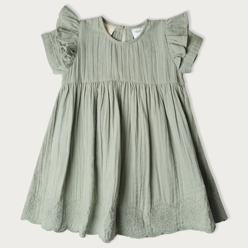 A sage green cotton gauze dress for toddlers, featuring ruffled cap sleeves, a gathered waist, and embroidered floral lace trim at the hem
