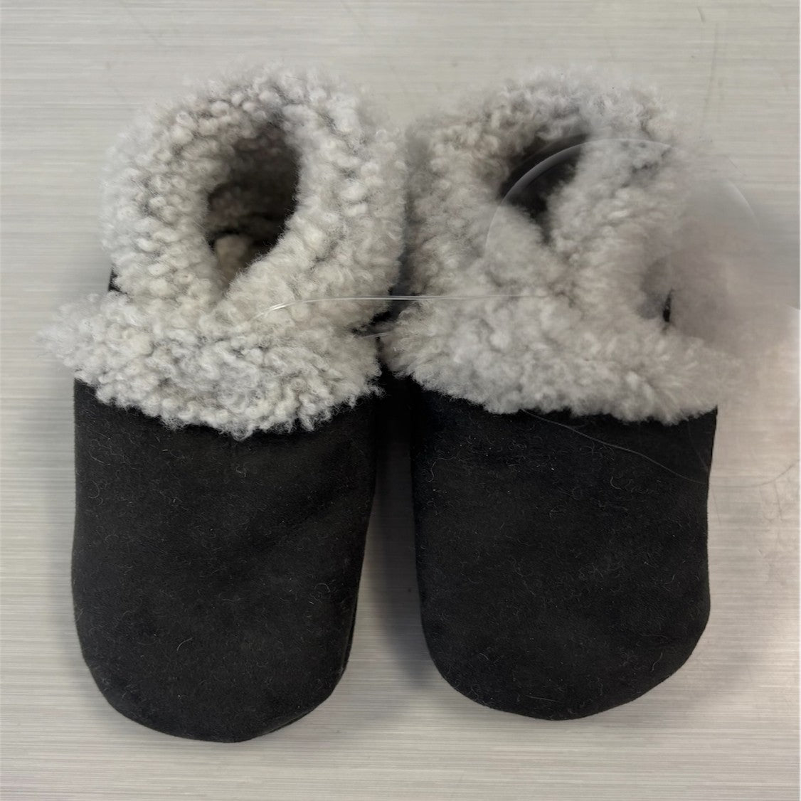A pair of dark grey lambskin booties with elastic closure, designed for babies.