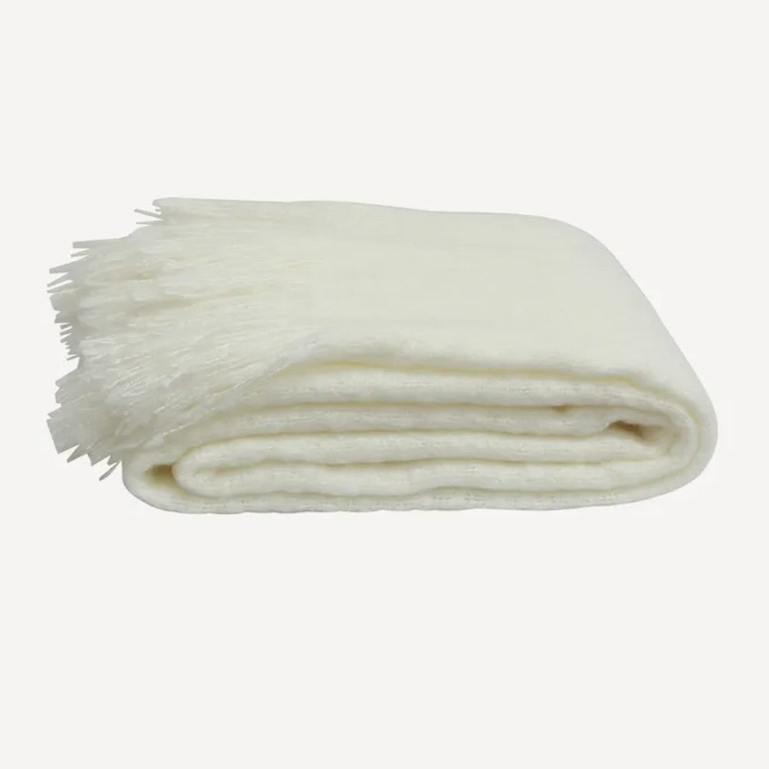 A folded off white throw with tassels, made of acrylic,