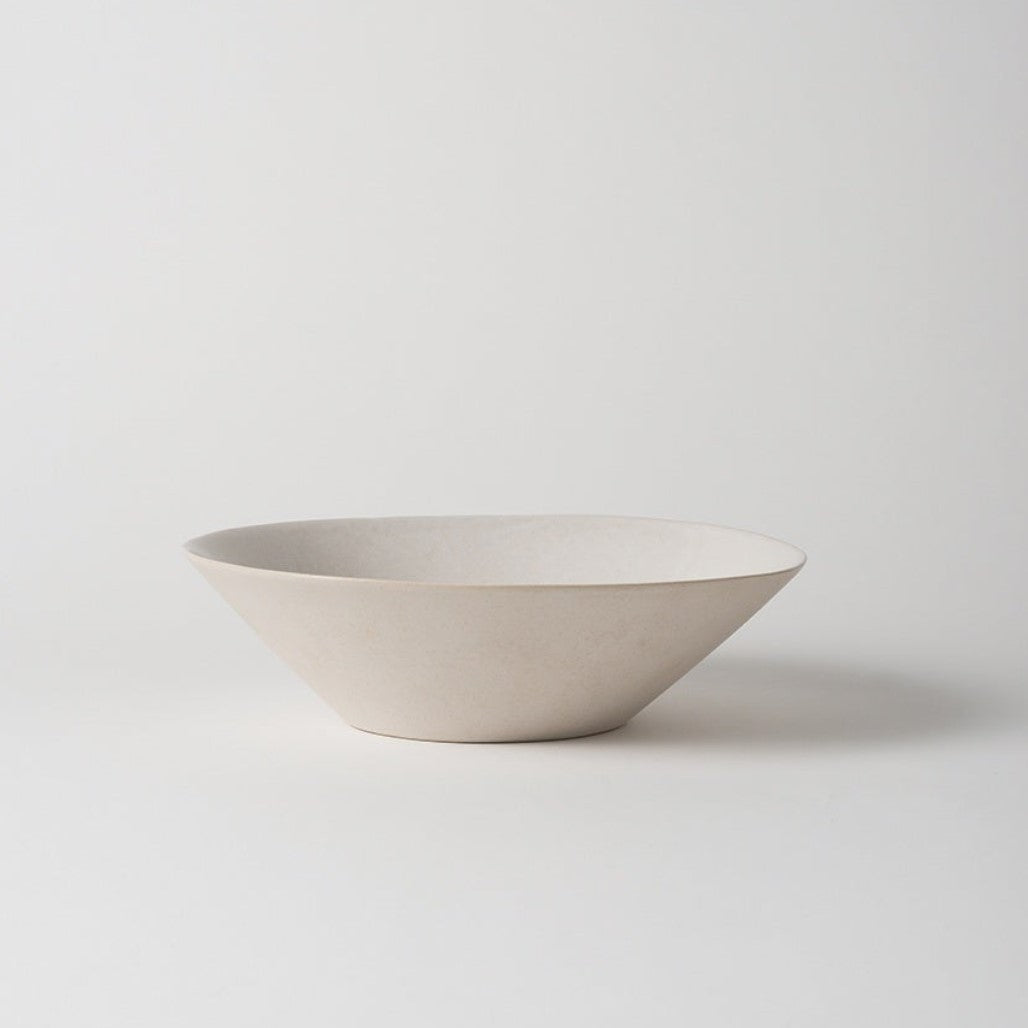 A white, handmade stoneware salad bowl with an organic shape