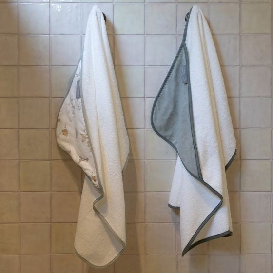 Two towels hanging on a tiled wall