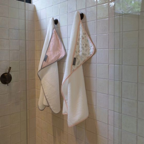 Two towels hanging on a tiled wall