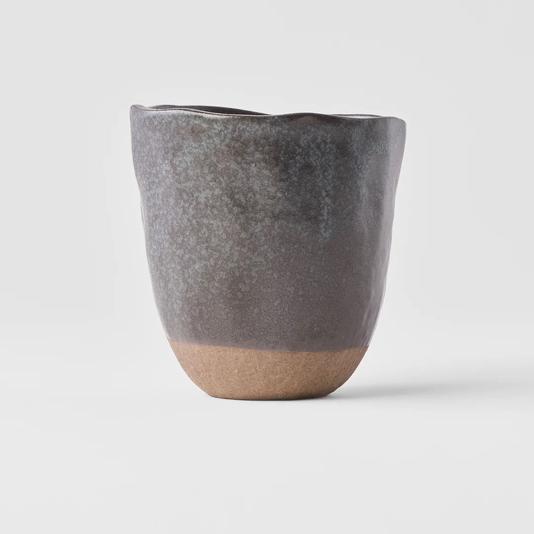 Lopsided black and bisque colored ceramic mug with a smooth finish.