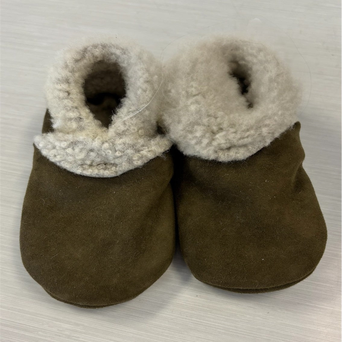 A pair of green lambskin booties with elastic closures, designed for babies.