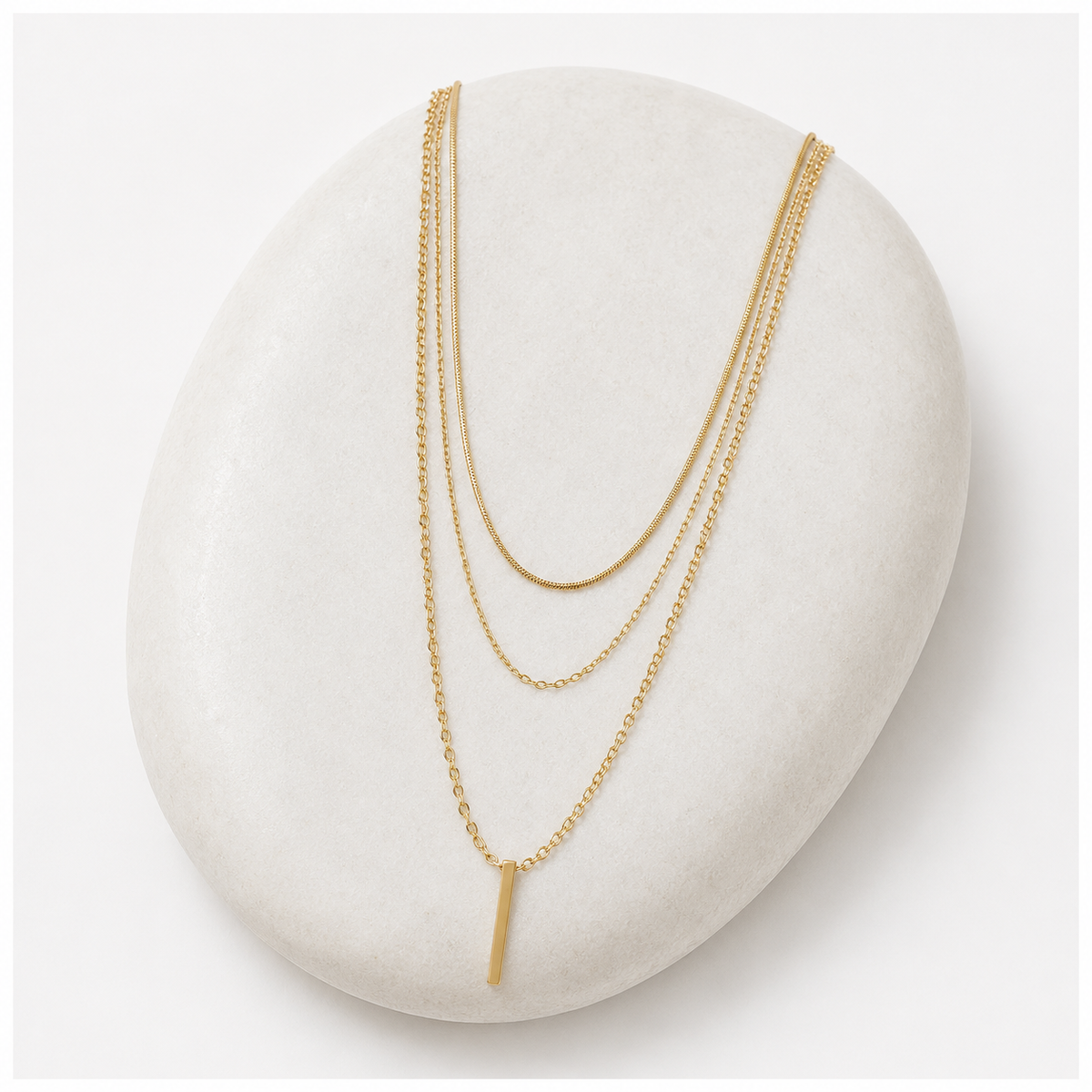 Two gold necklaces on a white stone surface