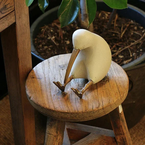 A wooden kiwi with brass feet finished with whitewashed