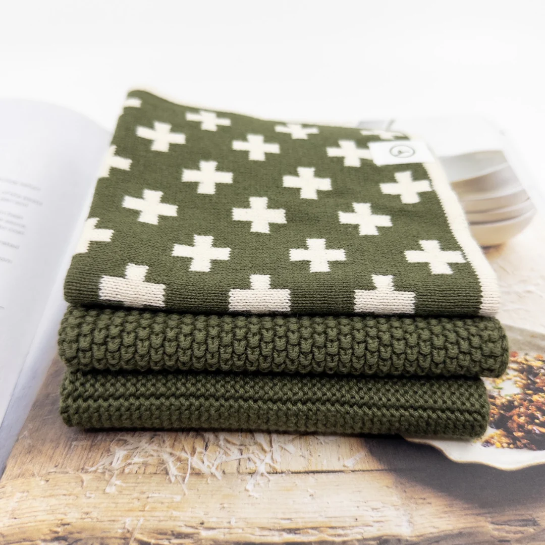 Stack of green dish cloths with white cross pattern
