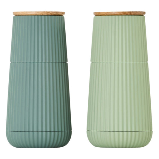 Two green ceramic salt and pepper shakers with wooden lids 
