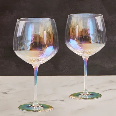 Two iridescent wine glasses on a marble surface with a dark background