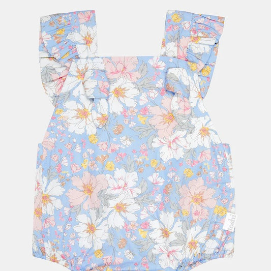 A blue floral romper with shoulder ties, elasticized waistband, and press studs for baby wear.