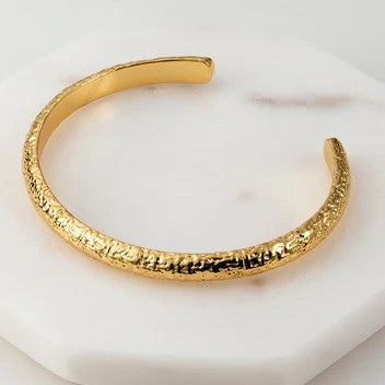 A gold-plated brass base cuff bracelet with a textured surface 