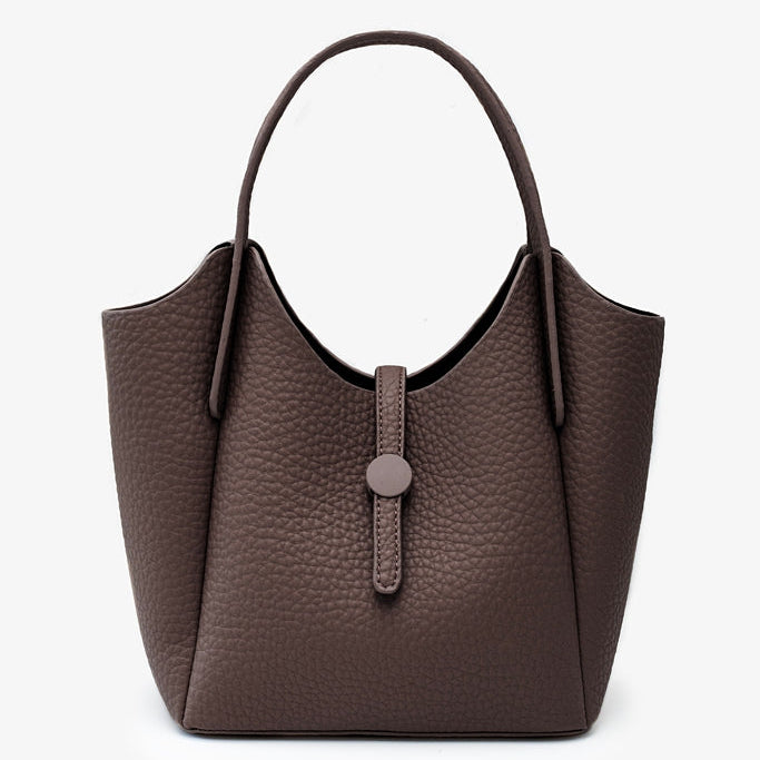 A dark brown pebbled leather handbag with a single top handle and a front strap closure with a round button, 