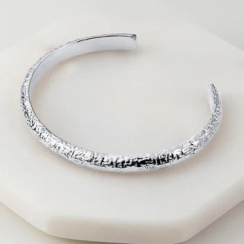 A silver-colored bracelet with a solid pattern 