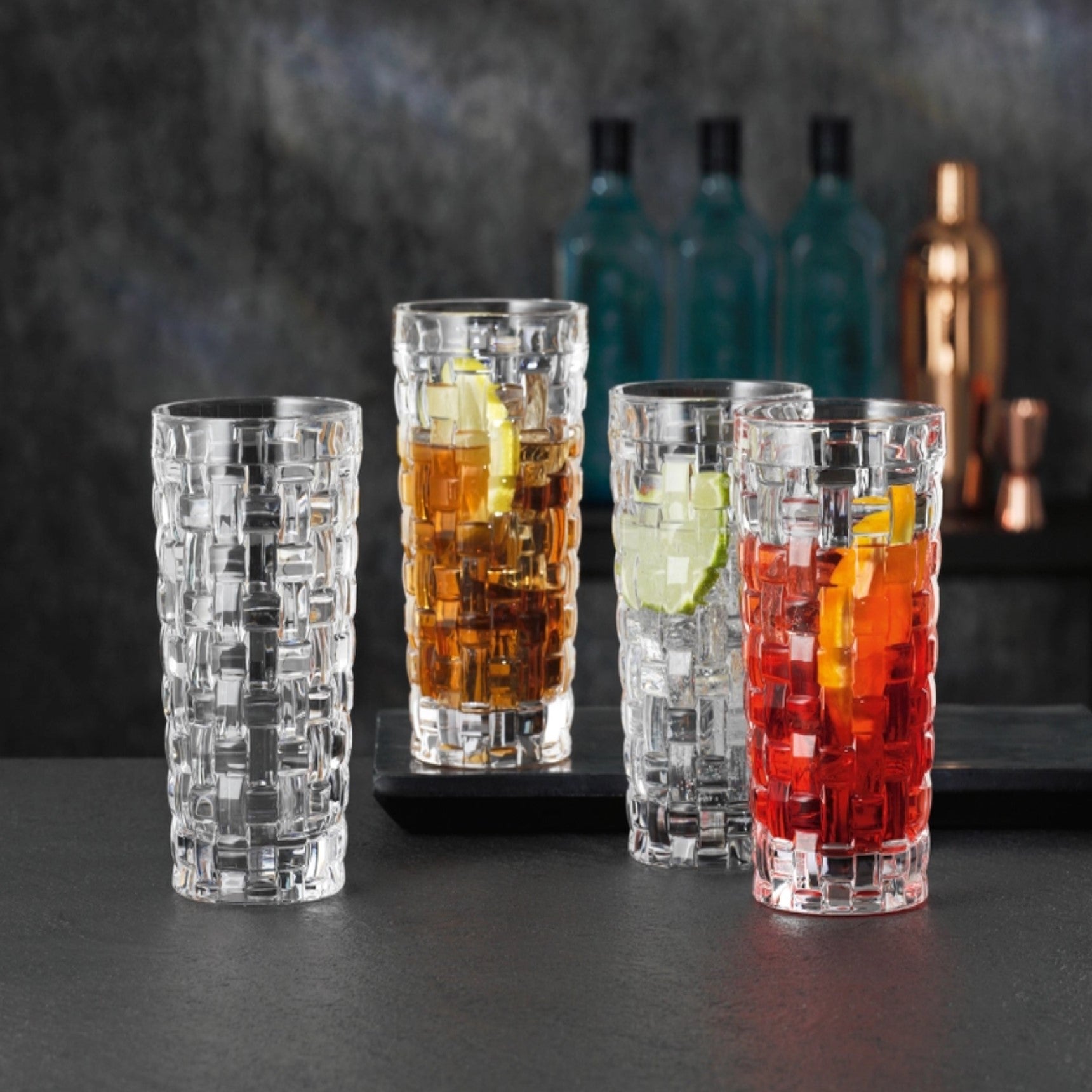 A set of four clear glass lowball glasses with a geometric pattern,
