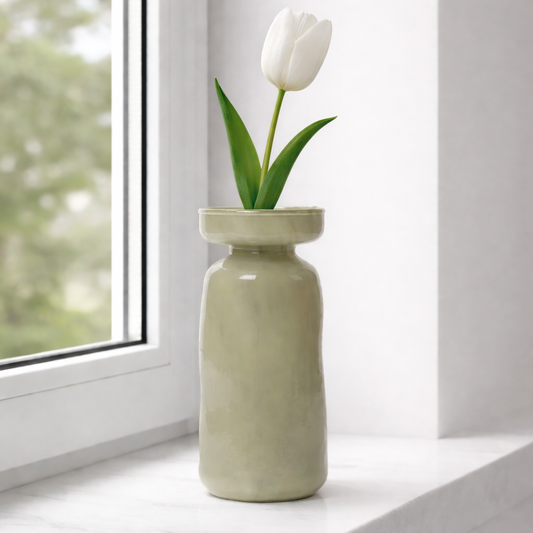 Green vase with a white tulip on a windowsill