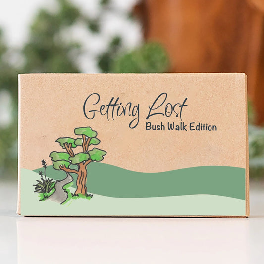 Kraft paper box with 'Getting Lost Bush Walk Edition' text and nature illustration on a blurred background
