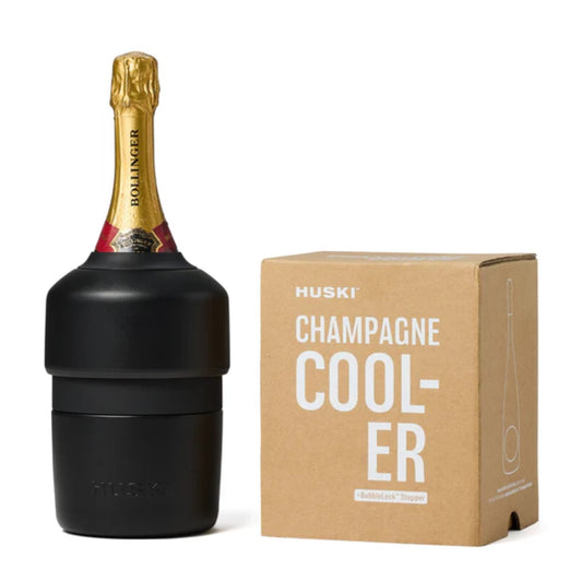 A black Huski Champagne Cooler with a bottle placed in it, next to its packaging box with the product name and brand visible.