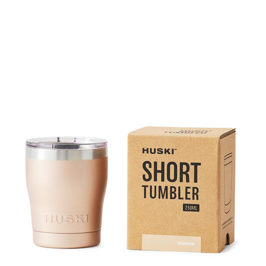 A chsmpagne Huski Short Tumbler 2.0 next to its packaging box.