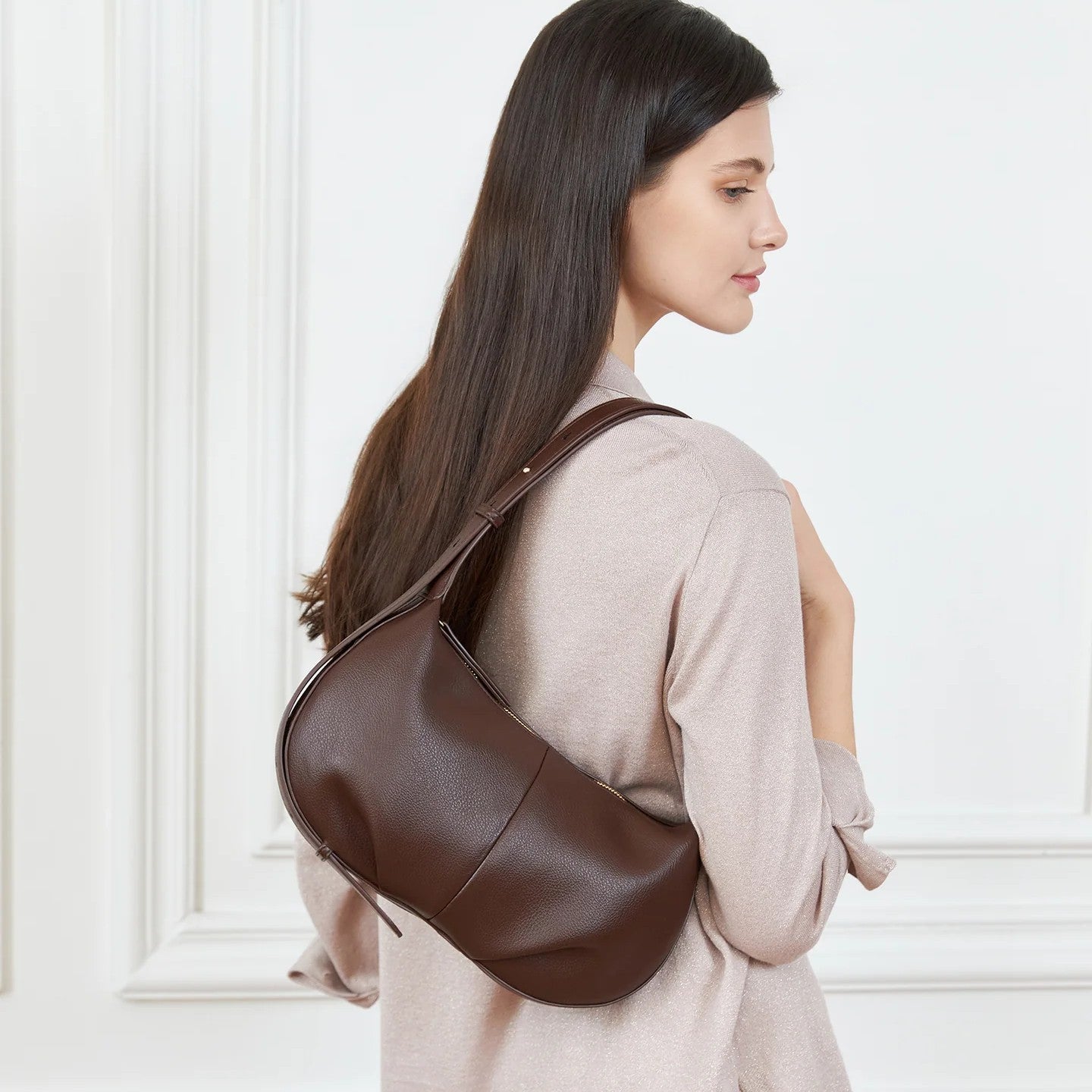 Woman carrying a brown vegan leather bag against a white background