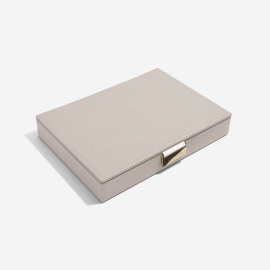 A taupe colored jewellery box lid with a grey velvet interior, featuring a vegan leather exterior and a metal clasp closure.