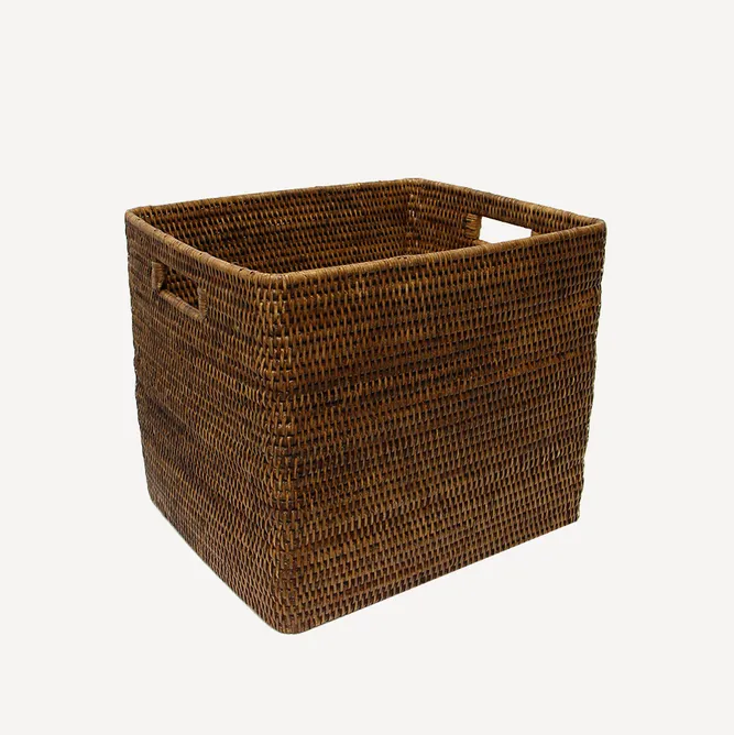 A brown natural rattan square basket with handles on the sides.