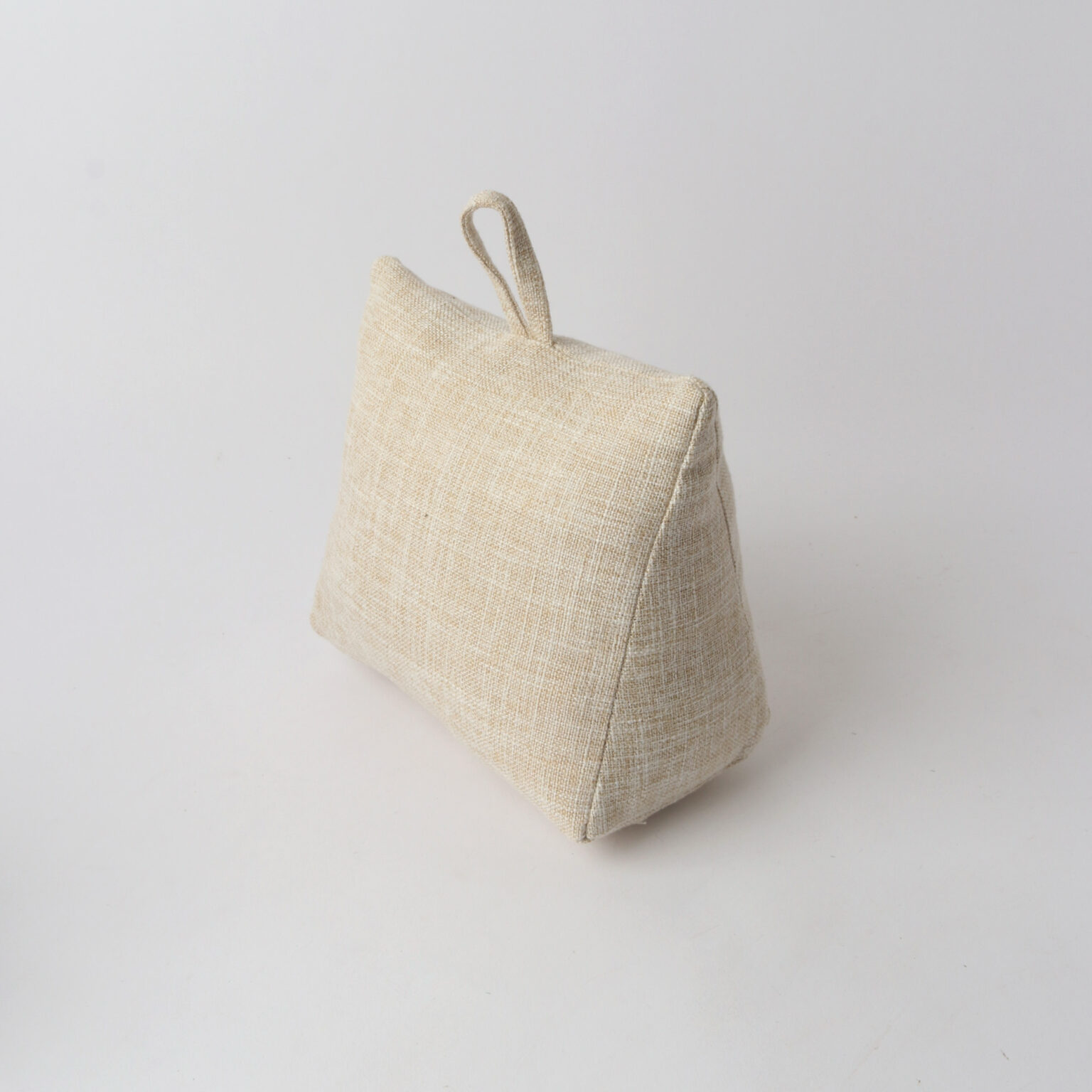 A small triangular fabric doorstop in a light beige linen-like material with a loop handle