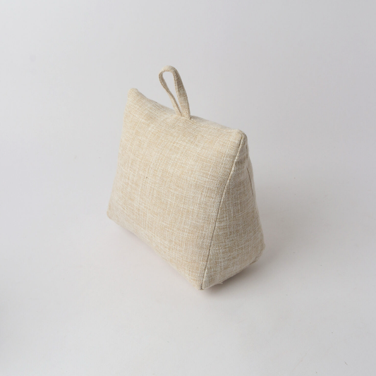 A small triangular fabric doorstop in a light beige linen-like material with a loop handle