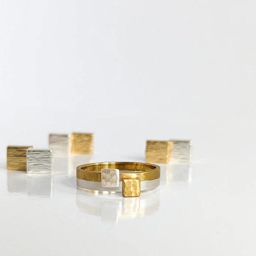 A sterling silver ring with a gold-colored square accent,