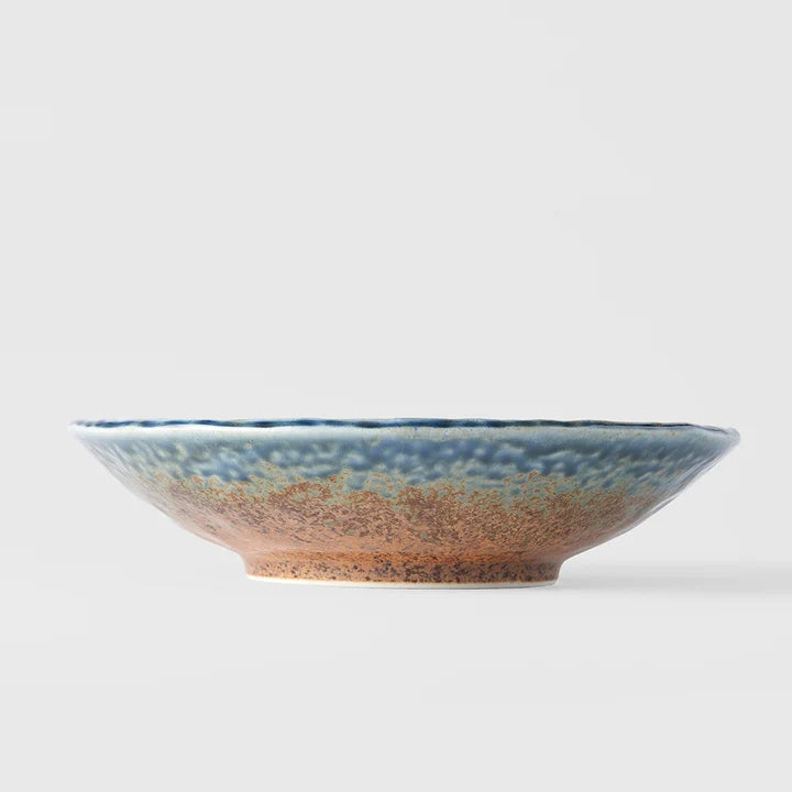 A wide ceramic bowl with a textured blue and brown glaze, 