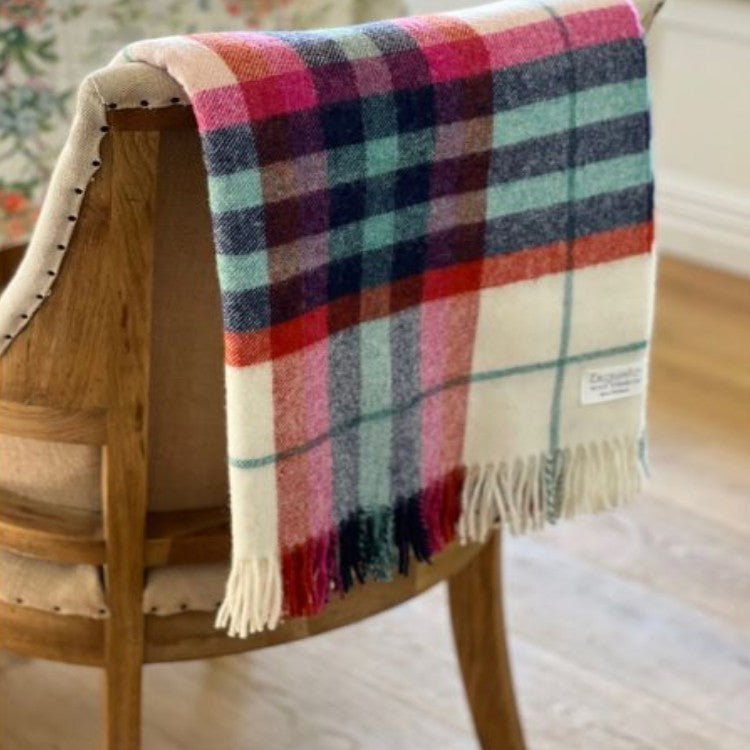 Colorful plaid wool blanket draped over a wooden chair with a blurred background