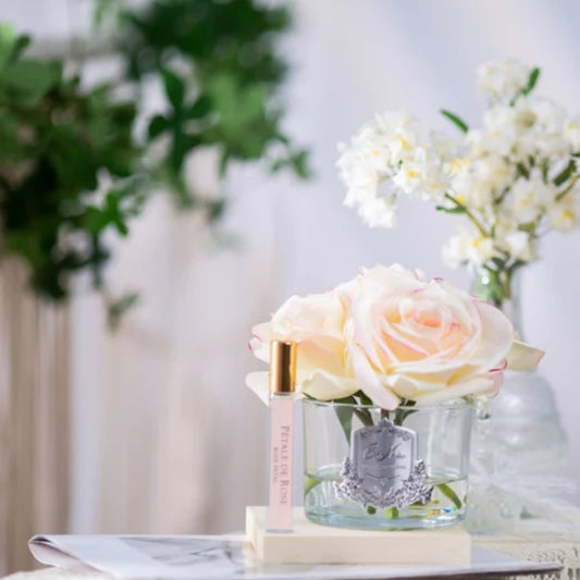 A life-like rose arrangement in a clear glass vase with a bottle of perfume, flower diffuser 