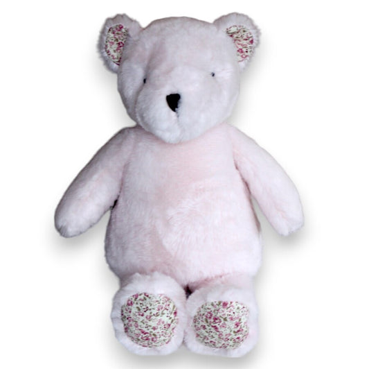 A plush pink teddy bear with floral patterned feet.