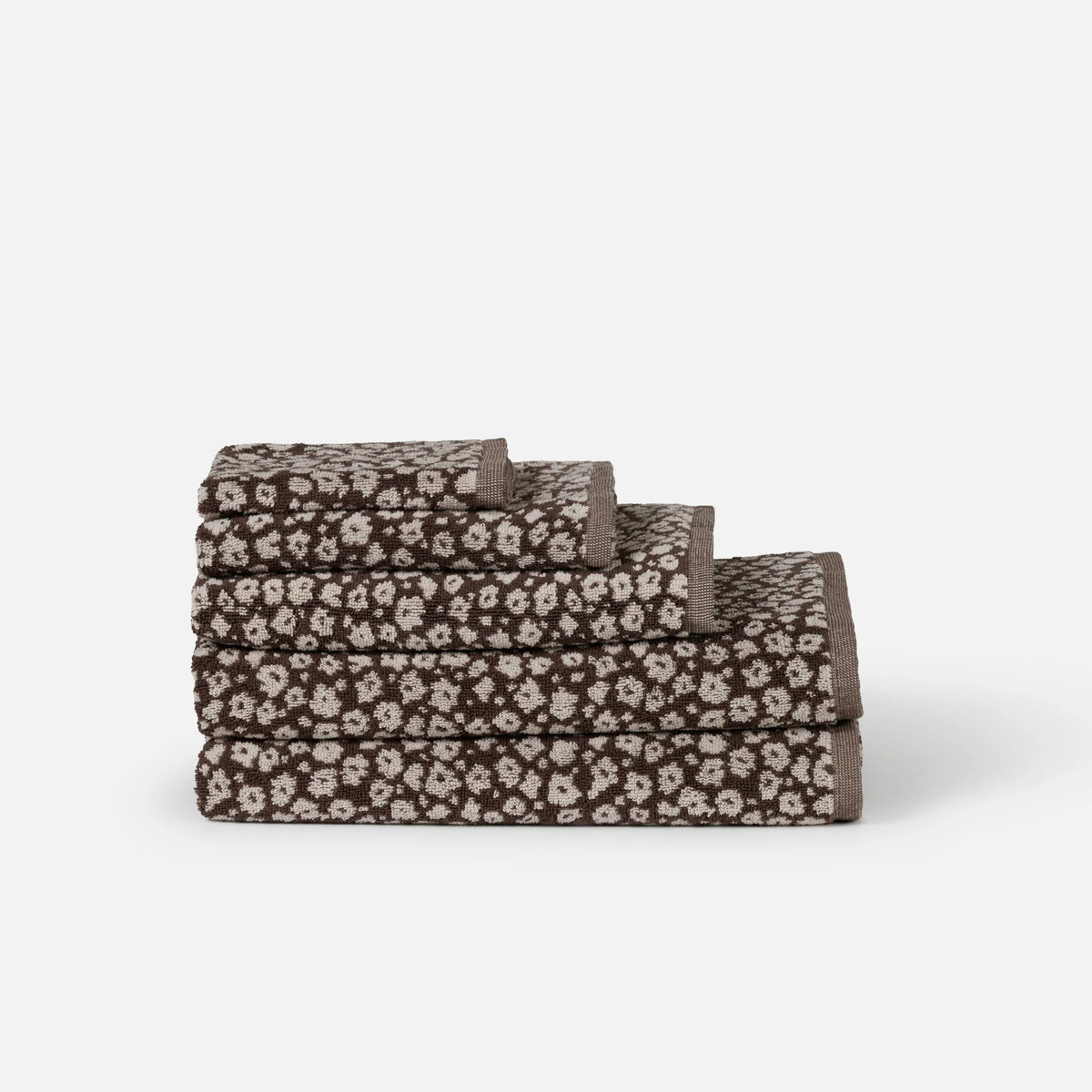 Four stacked rectangular towels with a dark brown and beige floral pattern, 