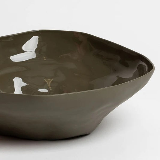 A large olive green ceramic serving bowl with a organic shape and a glazed interior.