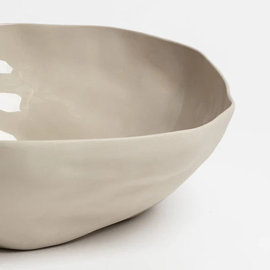 A large, beige, stoneware Haan serving bowl with an organic shape, displayed against a neutral background.