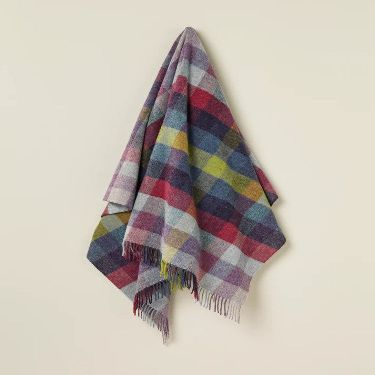 Multicolored plaid wool blanket draped over a light beige surface