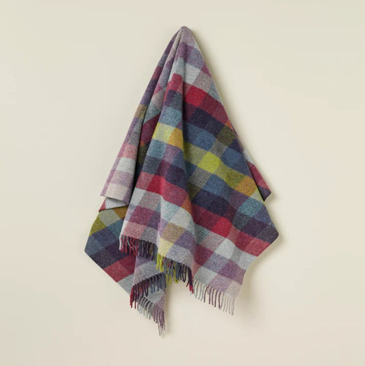 Multicolored plaid wool blanket draped over a light beige surface