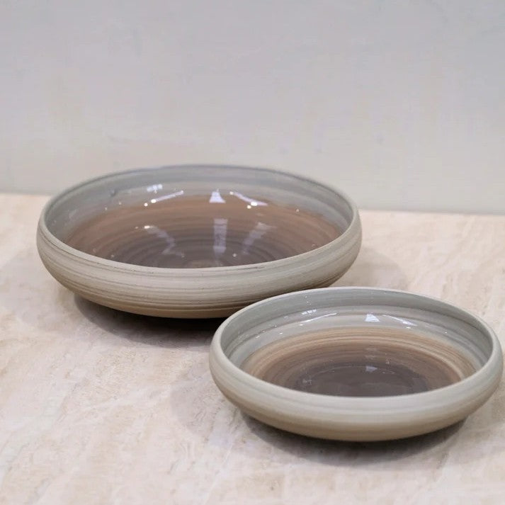 Two ceramic bowls with a gradient finish on a textured surface.