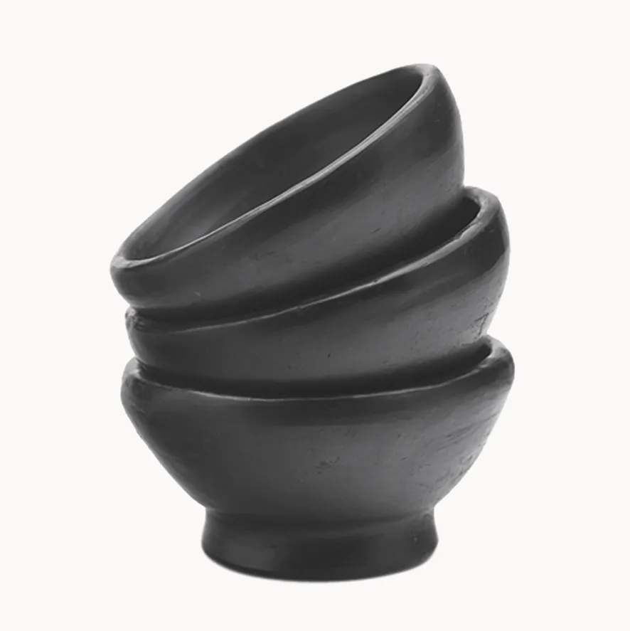 Stack of three black clay bowls on a white background