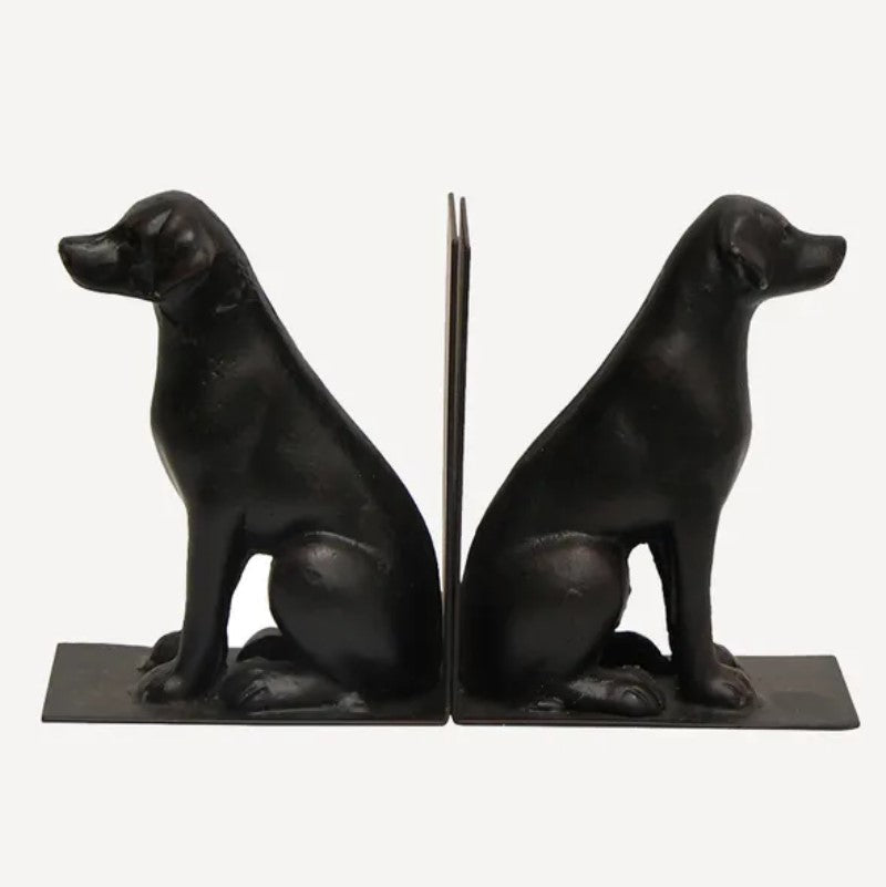A pair of black cast iron bookends in the shape of labrador retriever dogs sitting.