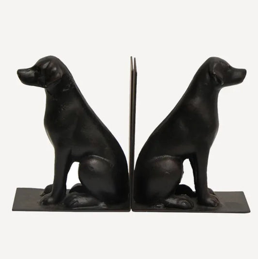 A pair of black cast iron bookends in the shape of labrador retriever dogs sitting.