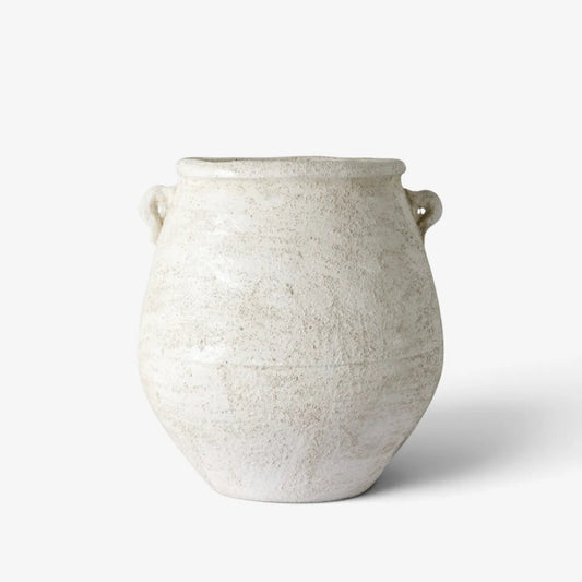A rustic, handcrafted ceramic vase with a textured off-white glaze and two small loop handles, set against a clean white background.