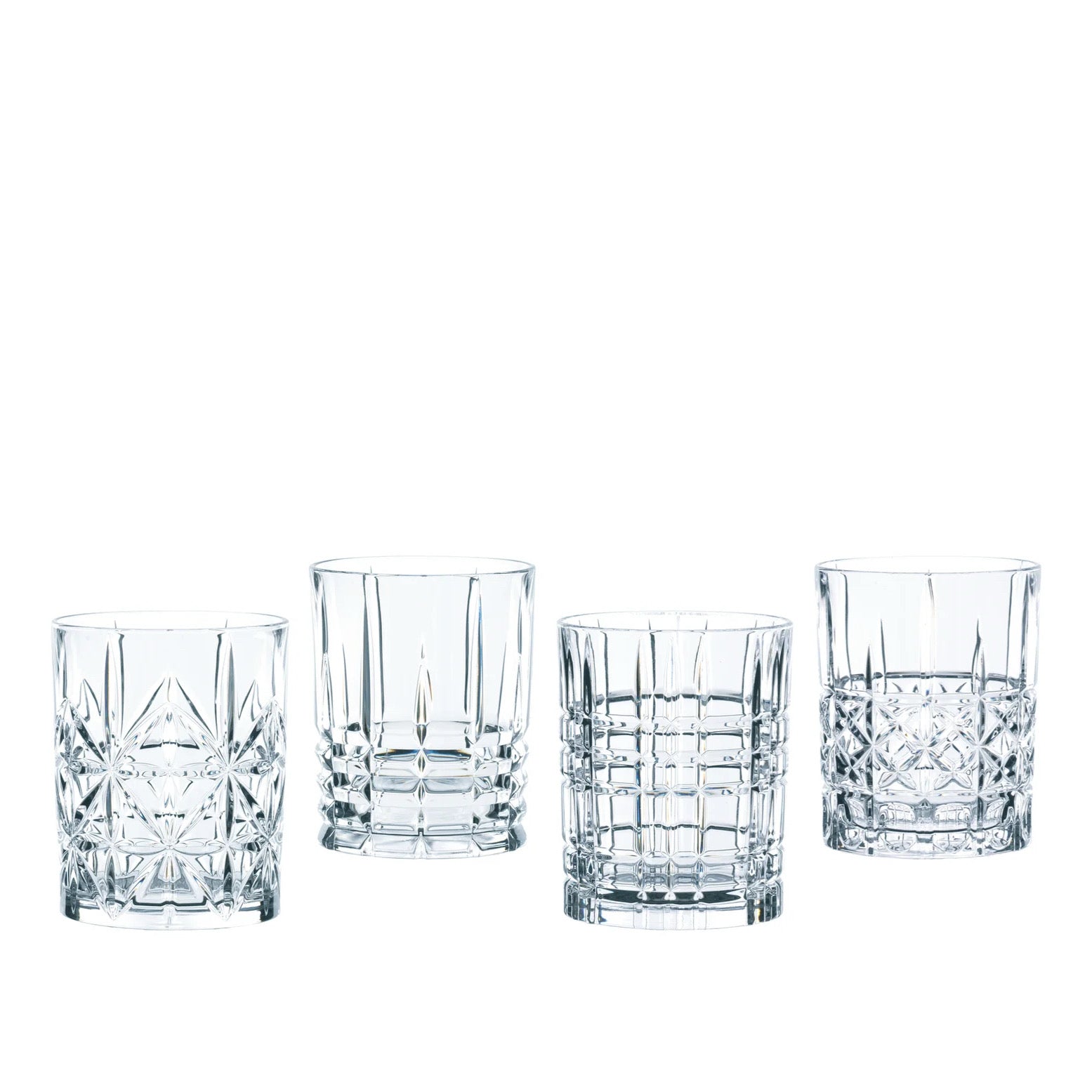 Four clear cut-crystal style rocks glasses with different geometric faceted patterns, arranged in a row on a plain white background.