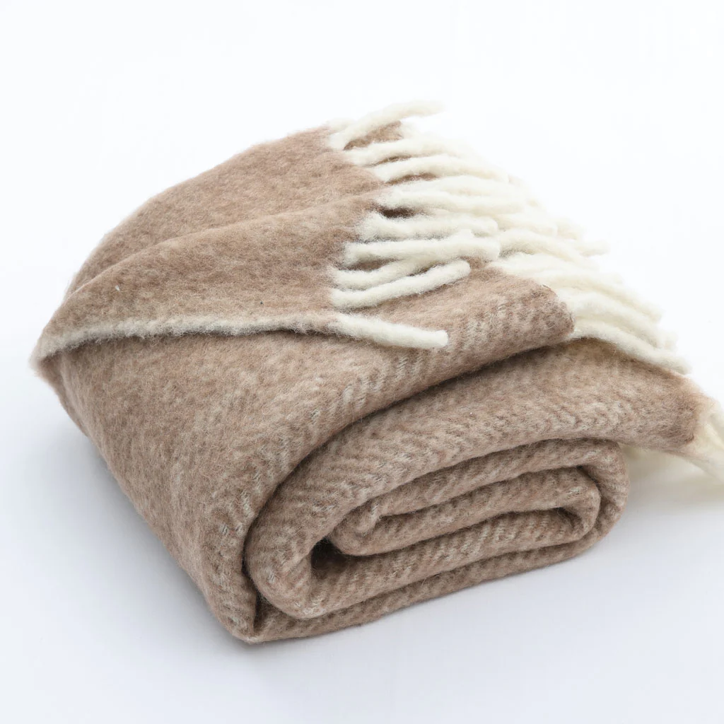 Folded beige blanket with white fringe