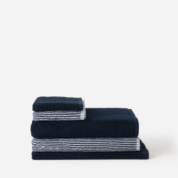 Stack of navy blue towels with white stripes on a white background