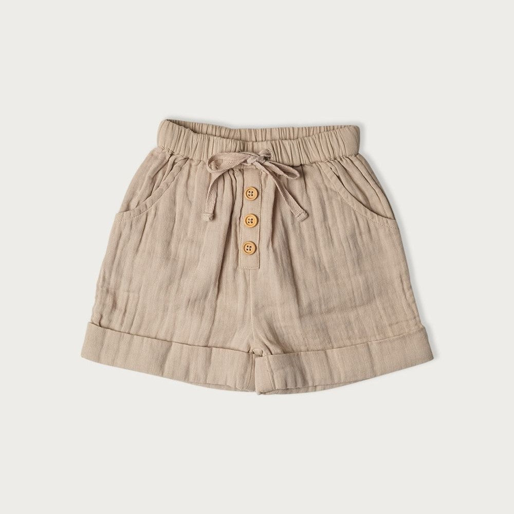 A pair of beige cotton muslin shorts with a tie waistband and wooden buttons for child 