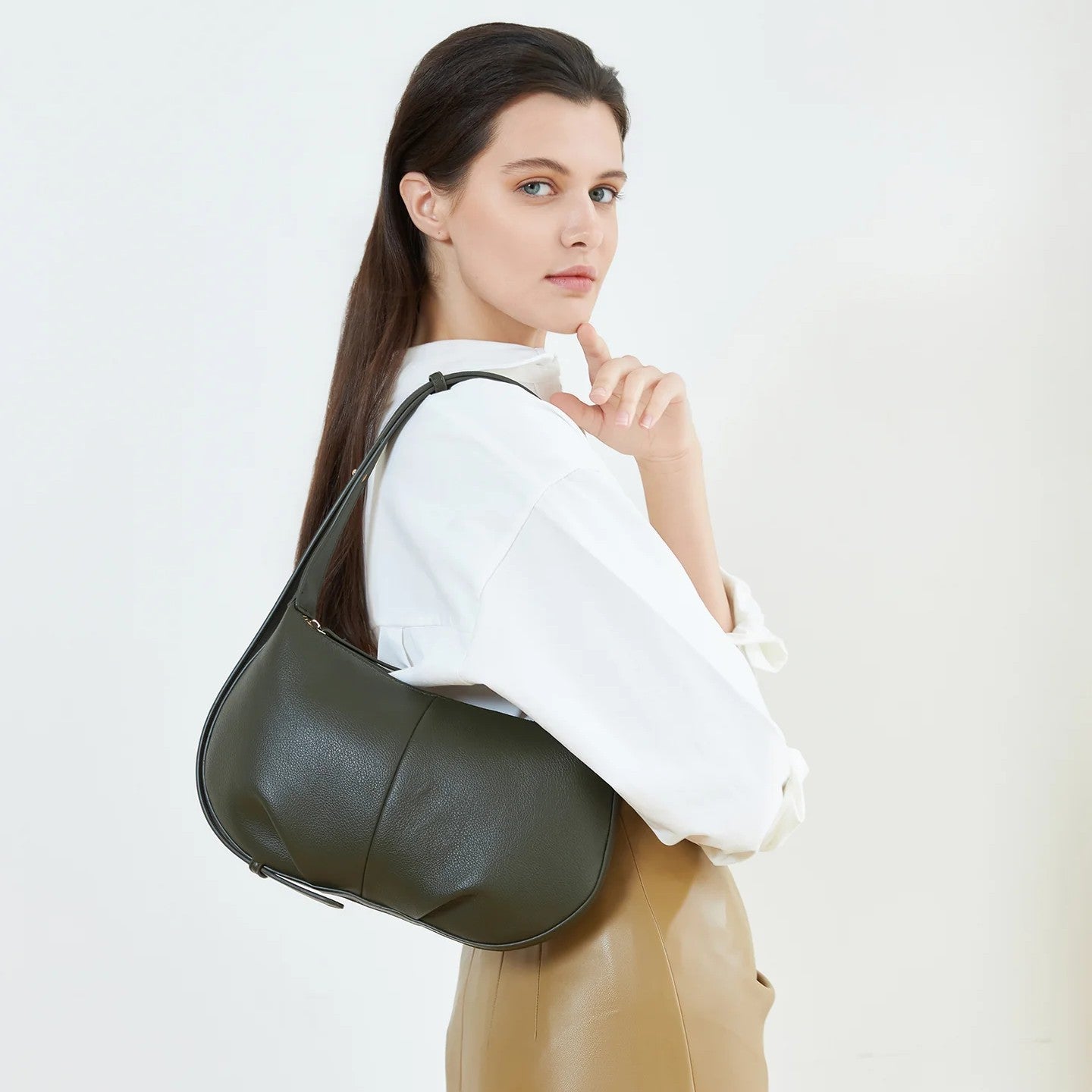 Woman holding a Olive green vegan leather handbag against a plain background