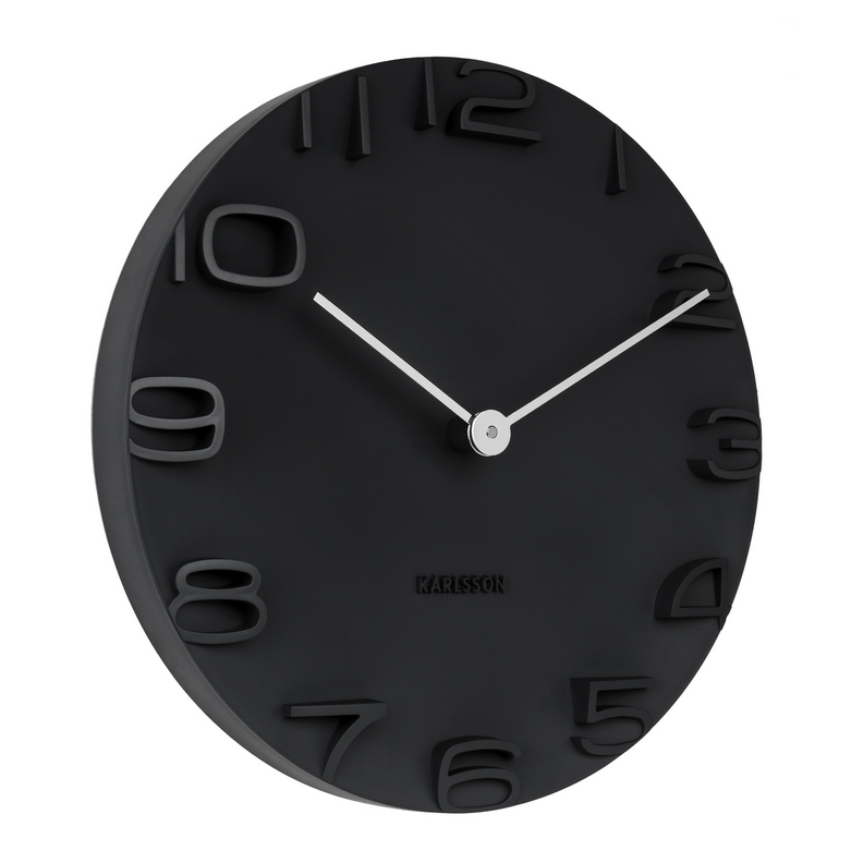 A black wall clock with chrome hands and numbers, branded by Karlsson, with a minimalist open face design.