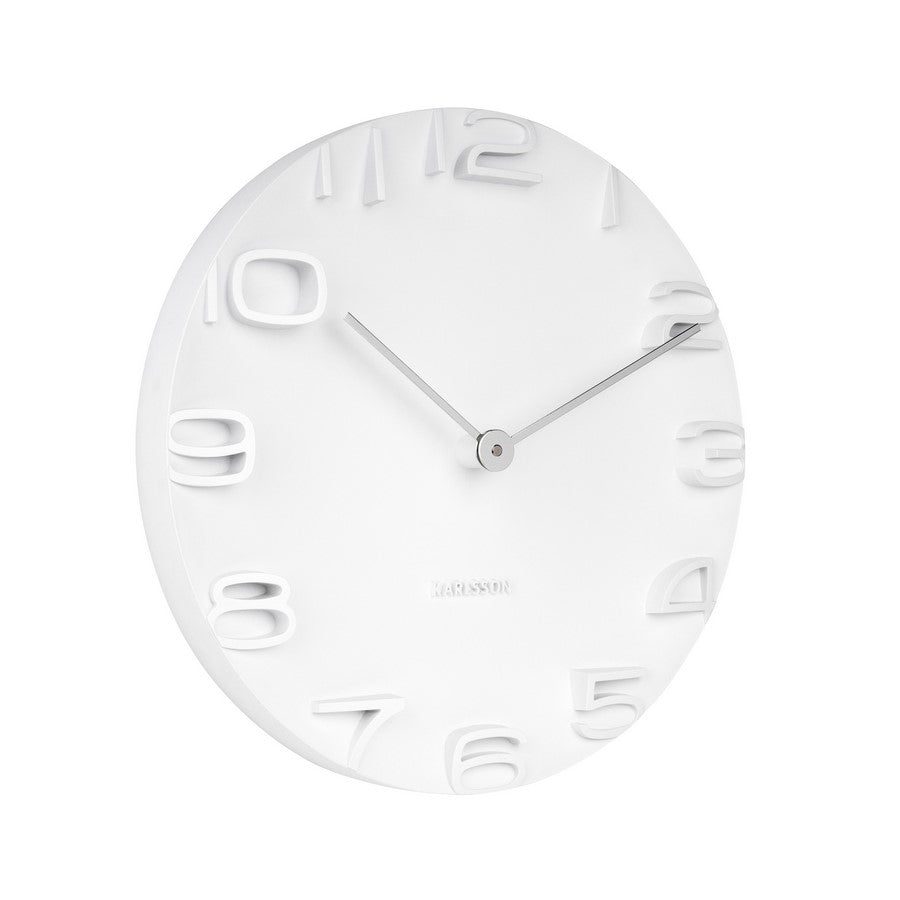 A white wall clock with chrome hands and numbers, mounted on a wall.