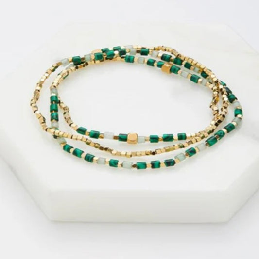 A wrap around beaded bracelets with green, gold, and white beads 